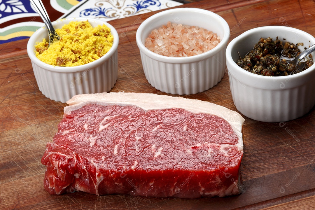 Bife de carne e temperos sobre tábua de madeira