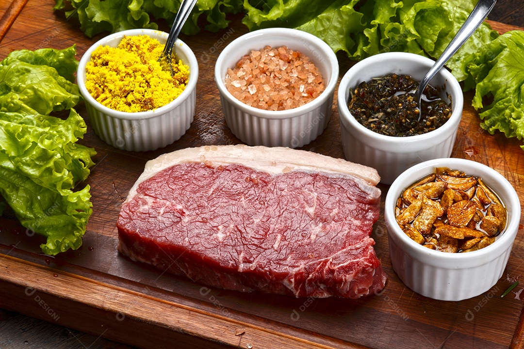 Bife de carne crua com temperos sobre tábua de madeira