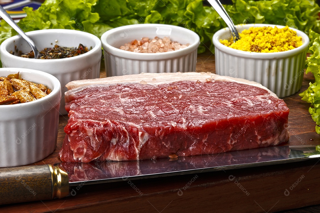 Bife de carne crua com temperos sobre tábua de madeira
