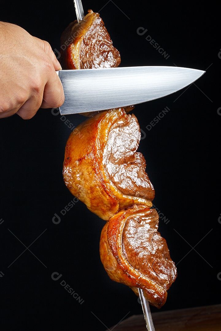 Espeto de picanha assado mão cortando carne