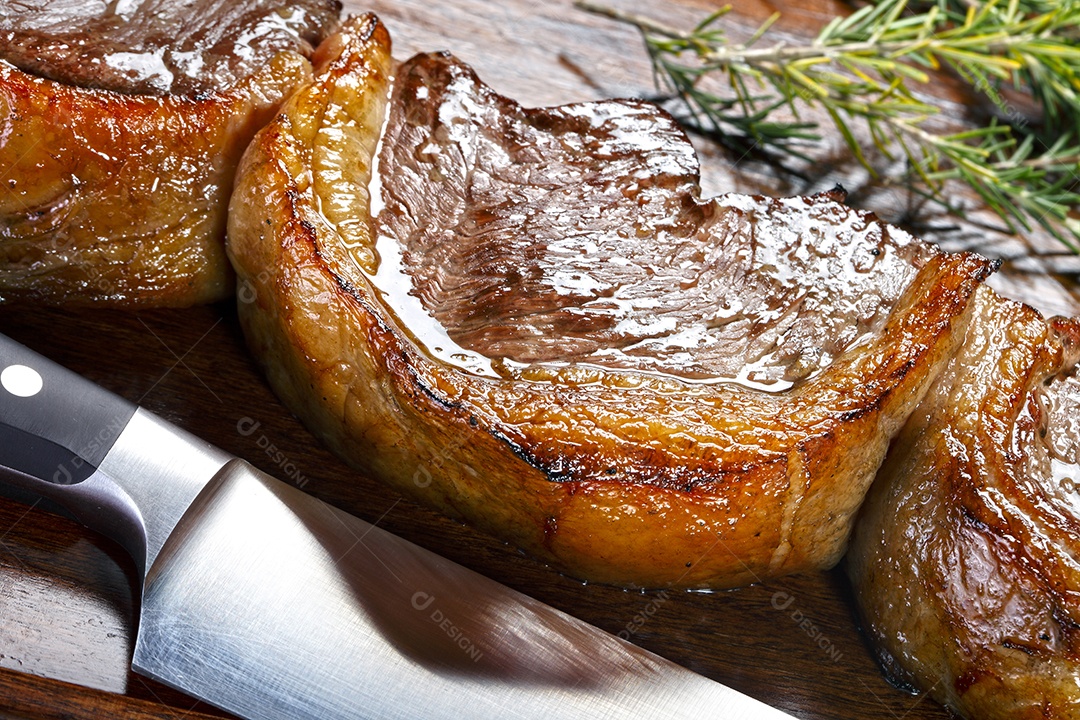 Picanha assada sobre tábua de madeira com faca ao lado