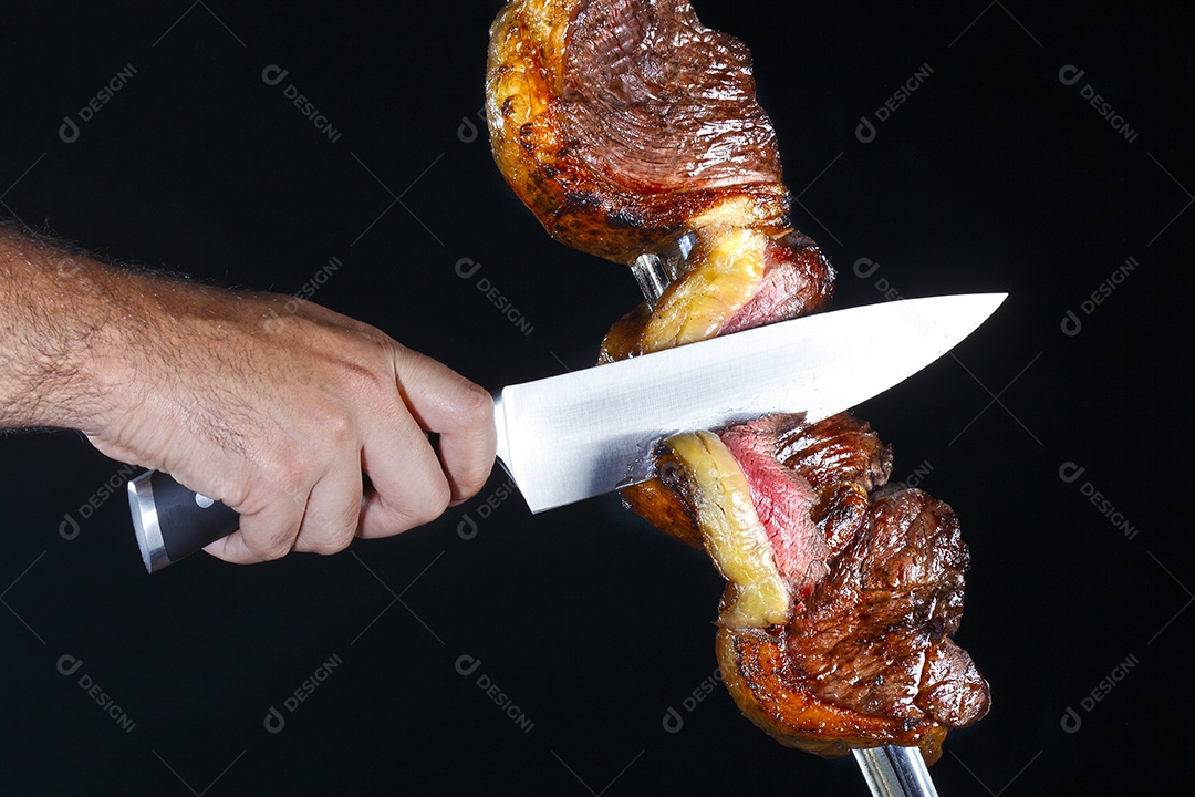 Mão cortando picanha assado no espeto