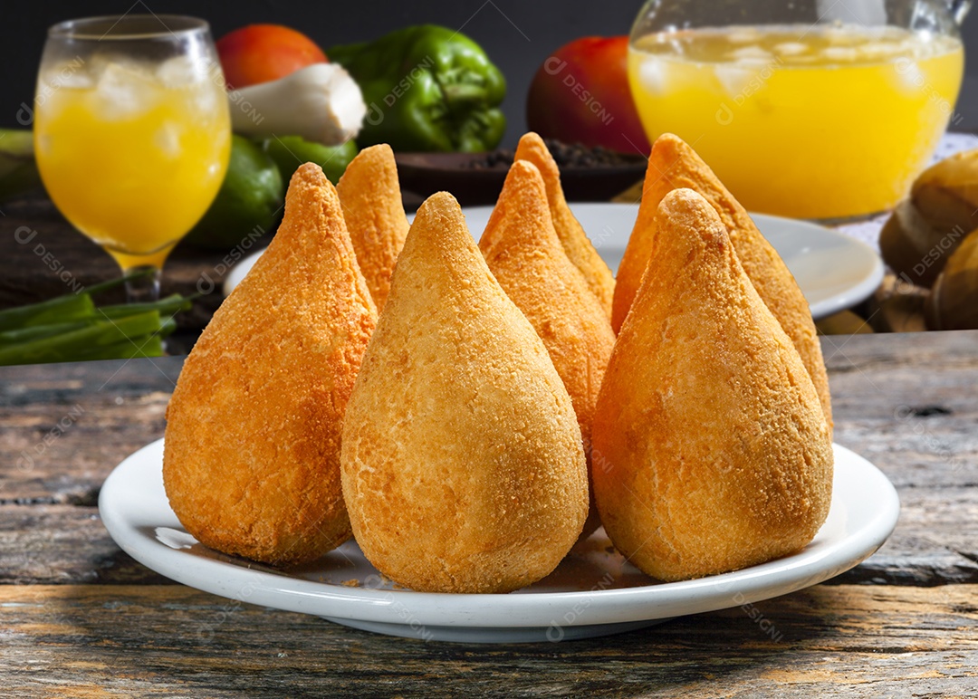 Coxinhas de frango sobre prato branco e suco