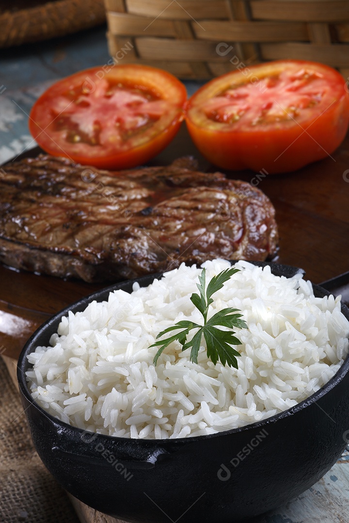 Panela de arroz com carne grelhada e tomates cortado ao meio
