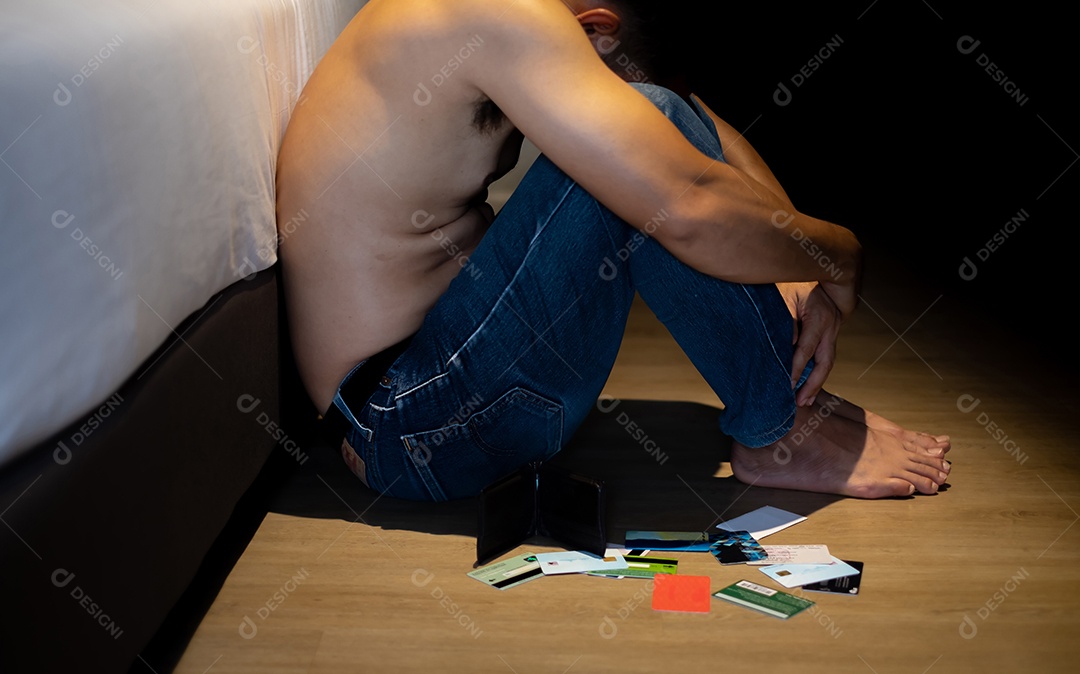 Homem de meia idade sem camisa sentado estressado abraçando os joelhos