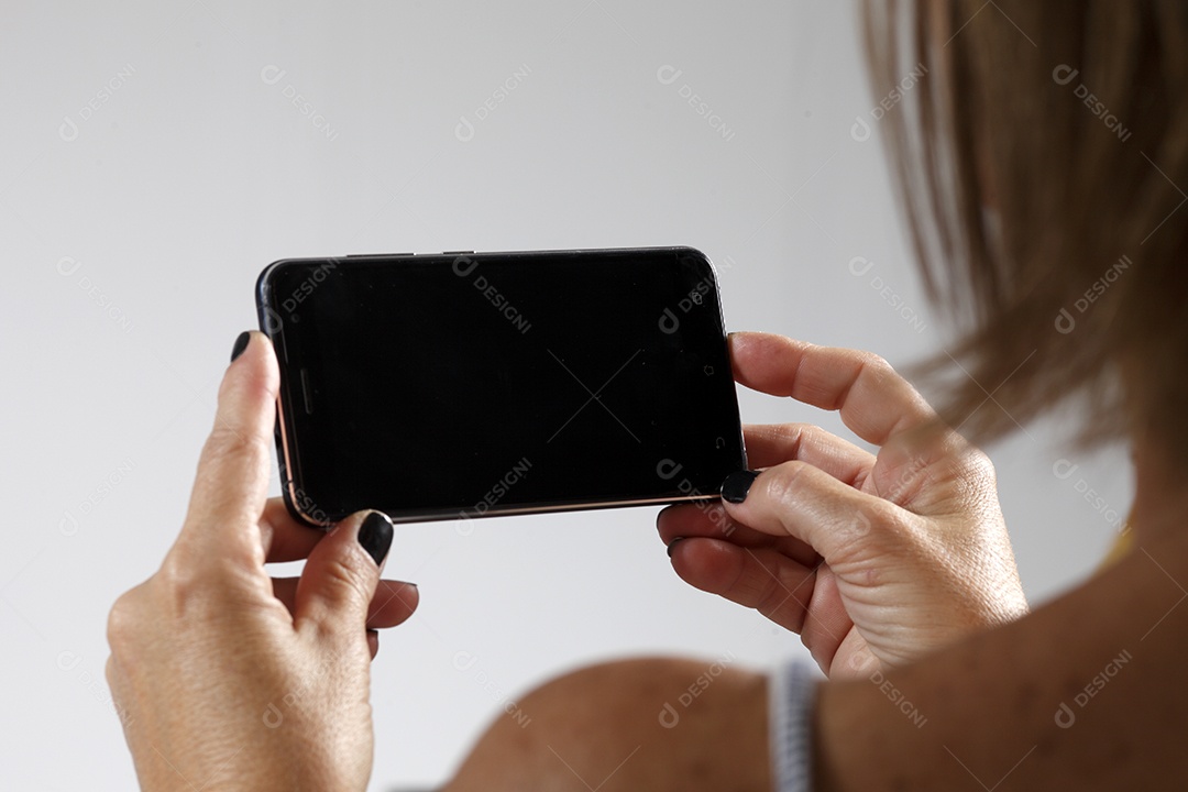 Mulher de cerca de 50 anos deitada vendo o celular