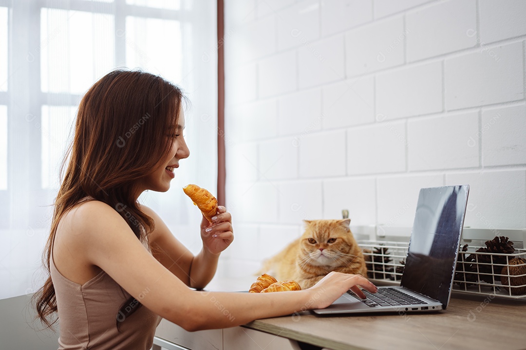 Mulher jovem asiática feliz trabalhando com computador portátil com gato bonito durante o dia de manhã.