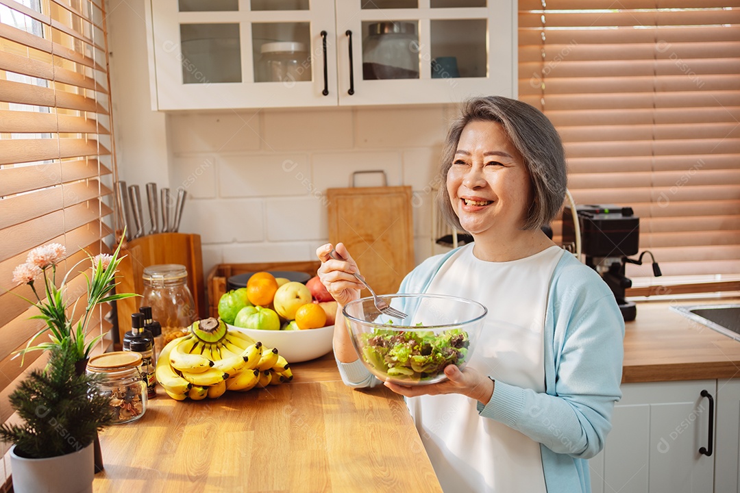 Mulher sênior asiática feliz comendo comida limpa para uma alimentação saudável na cozinha