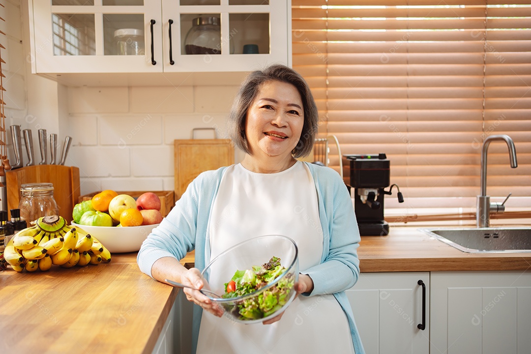 Mulher sênior asiática feliz comendo comida limpa para uma alimentação saudável na cozinha