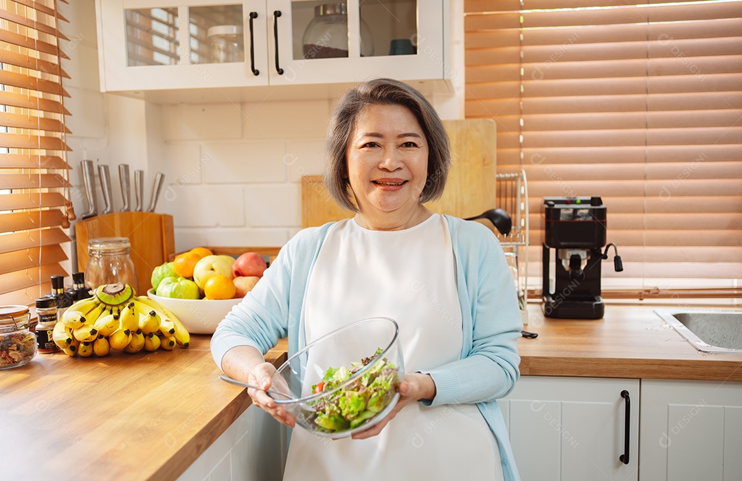 Mulher sênior asiática feliz comendo comida limpa para uma alimentação saudável na cozinha