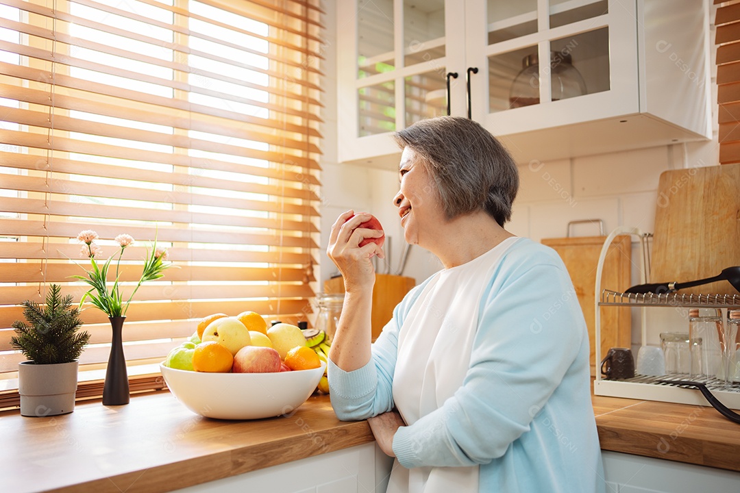 Mulher sênior asiática feliz comendo comida limpa para uma alimentação saudável na cozinha