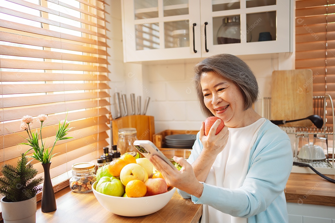 Mulher sênior asiática feliz comendo comida limpa para uma alimentação saudável na cozinha