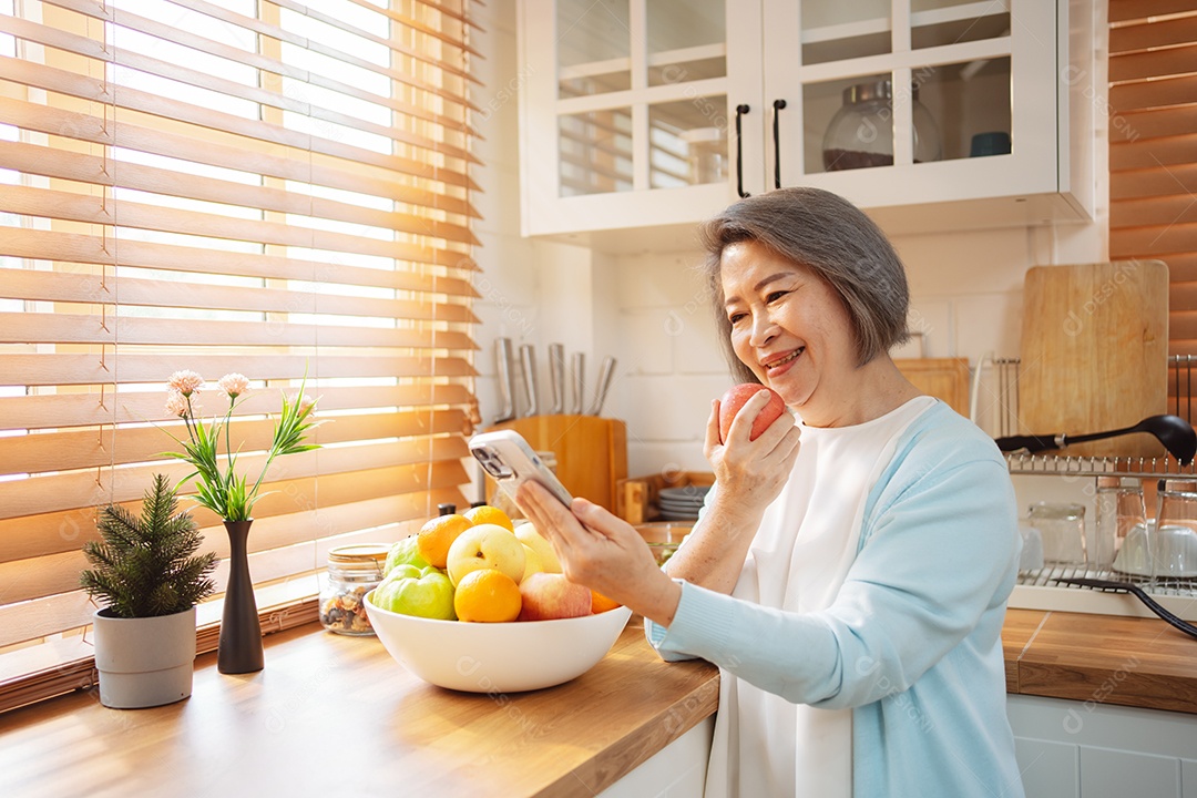 Mulher sênior asiática feliz comendo comida limpa para uma alimentação saudável na cozinha