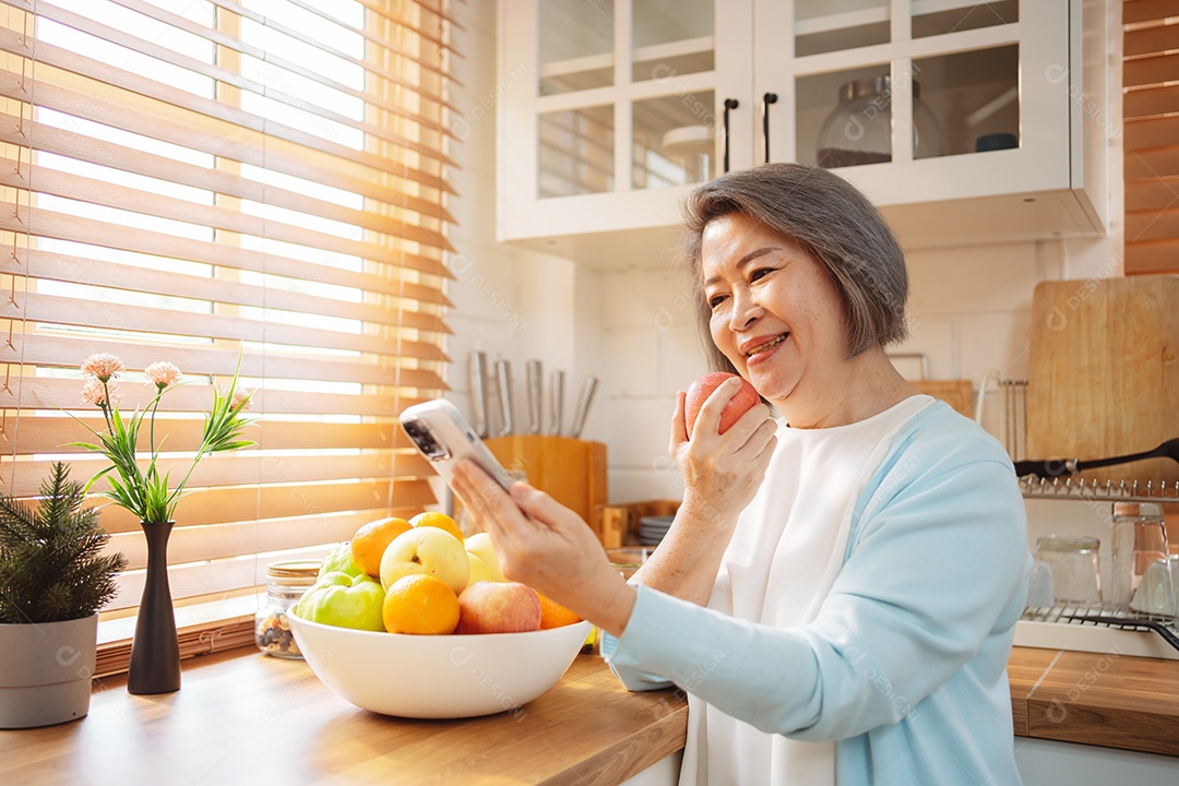 Mulher sênior asiática feliz comendo comida limpa para uma alimentação saudável na cozinha
