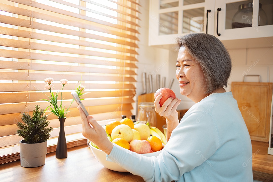 Mulher sênior asiática feliz comendo comida limpa para uma alimentação saudável na cozinha