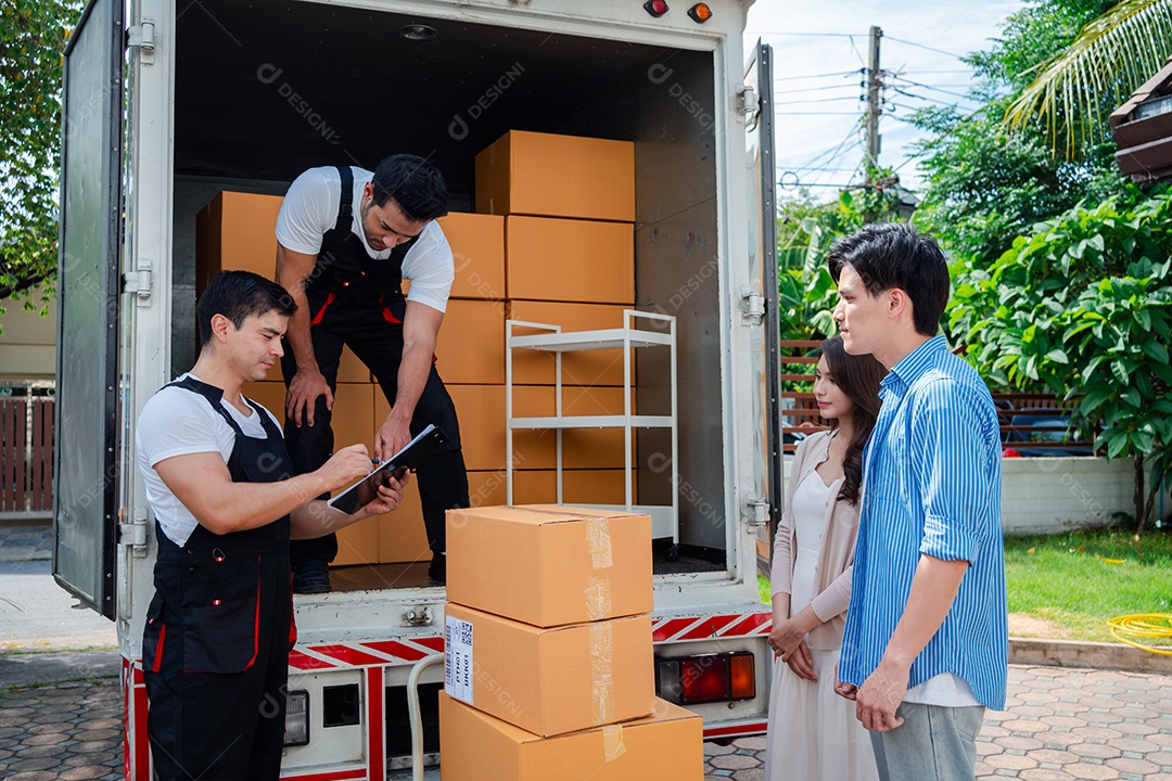 Verificação de casal asiático ao descarregar caixas e móveis de uma caminhonete para uma nova casa