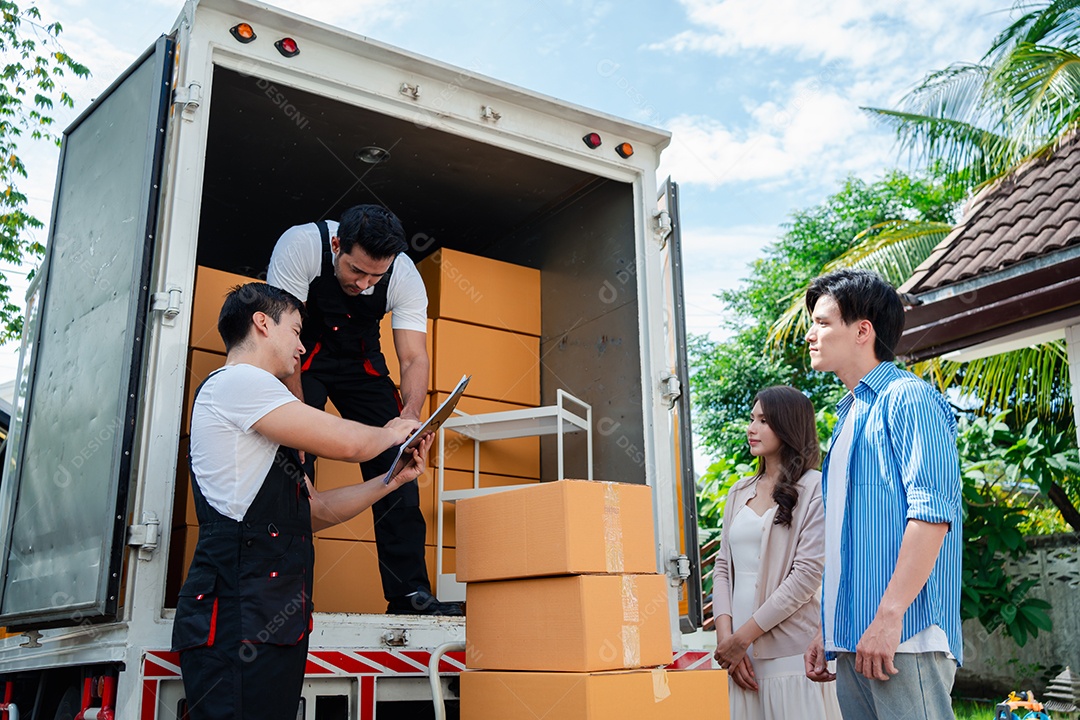 Verificação de casal asiático ao descarregar caixas e móveis de uma caminhonete para uma nova casa