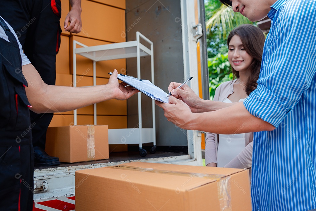 Verificação de casal asiático ao descarregar caixas e móveis de uma caminhonete para uma nova casa