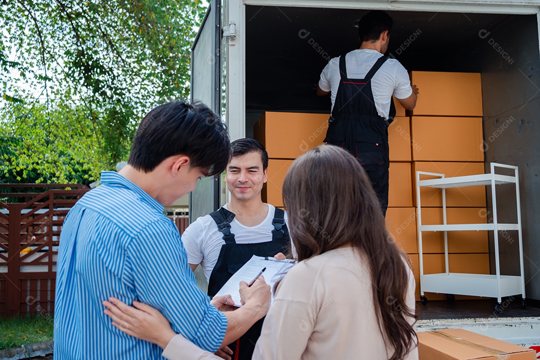 Verificação de casal asiático ao descarregar caixas e móveis de uma caminhonete para uma nova casa