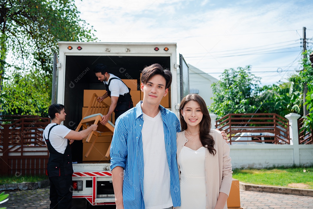 Verificação de casal asiático ao descarregar caixas e móveis de uma caminhonete para uma nova casa