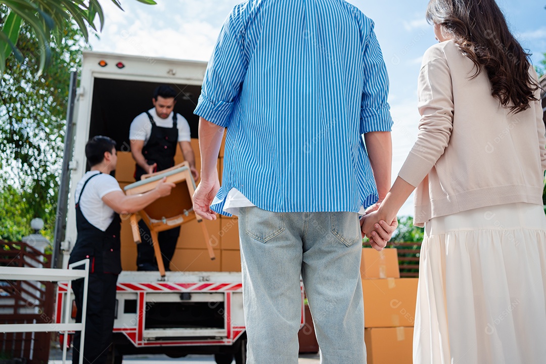 Verificação de casal asiático ao descarregar caixas e móveis de uma caminhonete para uma nova casa