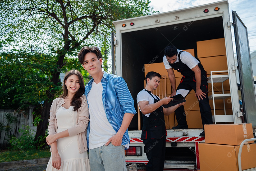 Verificação de casal asiático ao descarregar caixas e móveis de uma caminhonete para uma nova casa