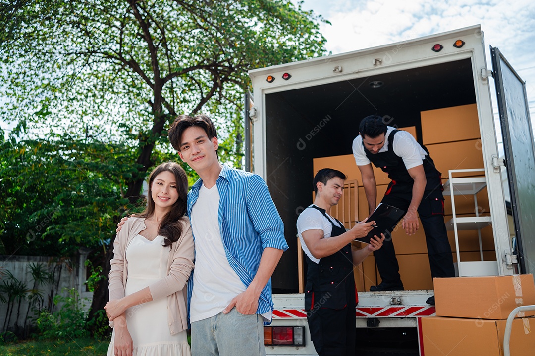 Verificação de casal asiático ao descarregar caixas e móveis de uma caminhonete para uma nova casa