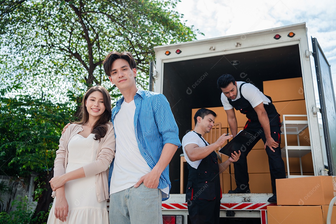 Verificação de casal asiático ao descarregar caixas e móveis de uma caminhonete para uma nova casa