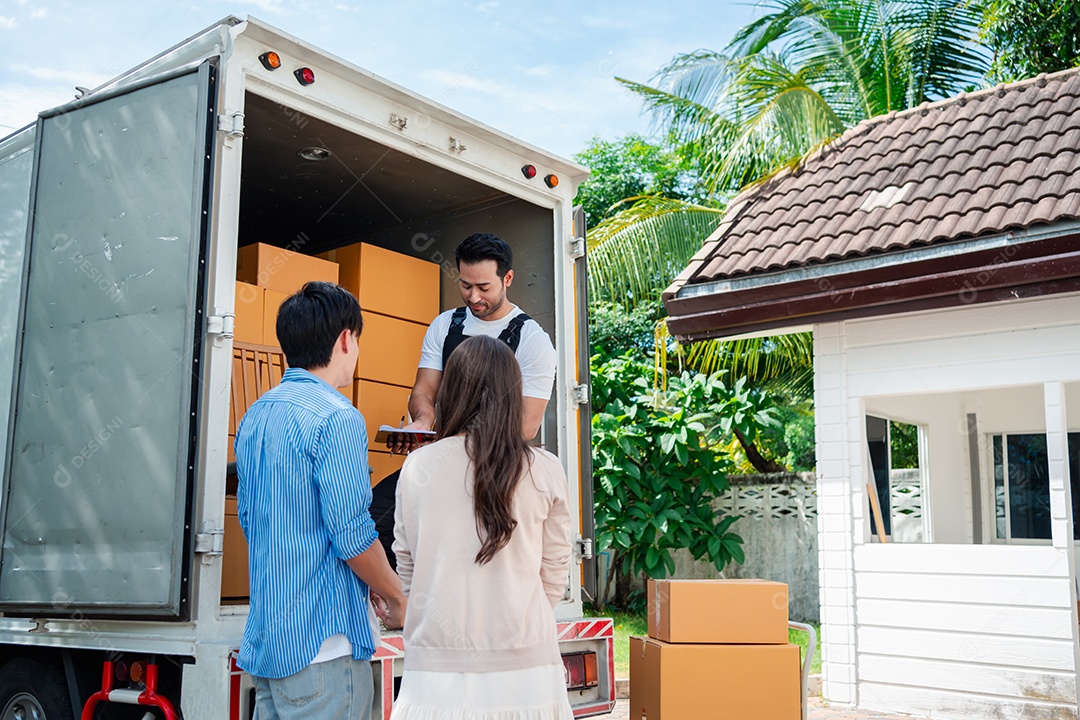 Verificação de casal asiático ao descarregar caixas e móveis de uma caminhonete para uma nova casa