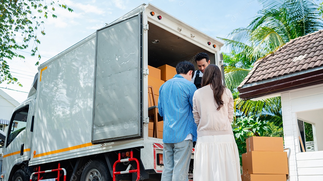 Verificação de casal asiático ao descarregar caixas e móveis de uma caminhonete para uma nova casa