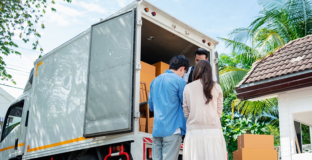 Verificação de casal asiático ao descarregar caixas e móveis de uma caminhonete para uma nova casa