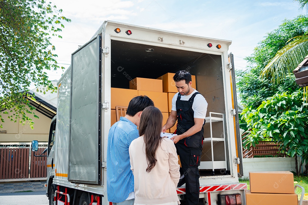 Verificação de casal asiático ao descarregar caixas e móveis de uma caminhonete para uma nova casa