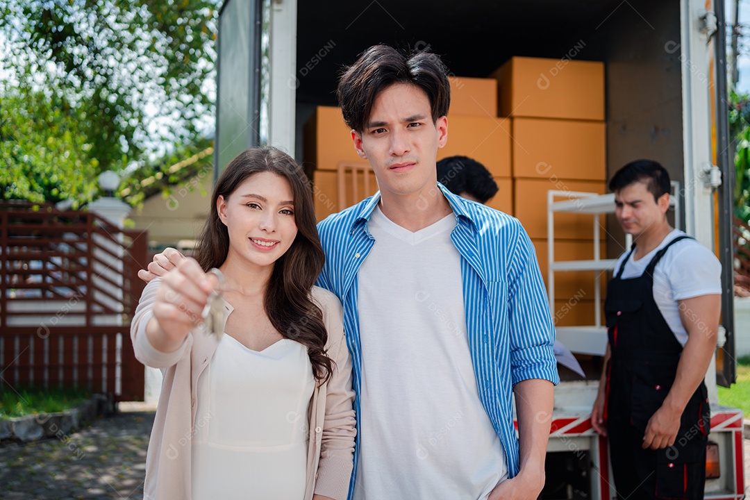 Verificação de casal asiático ao descarregar caixas e móveis de uma caminhonete para uma nova casa