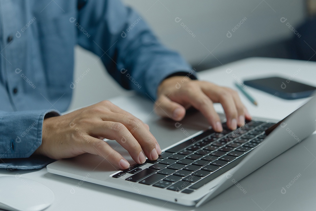 Homem digitando no teclado do computador portátil, procurando informações ou fazendo trabalho freelance.