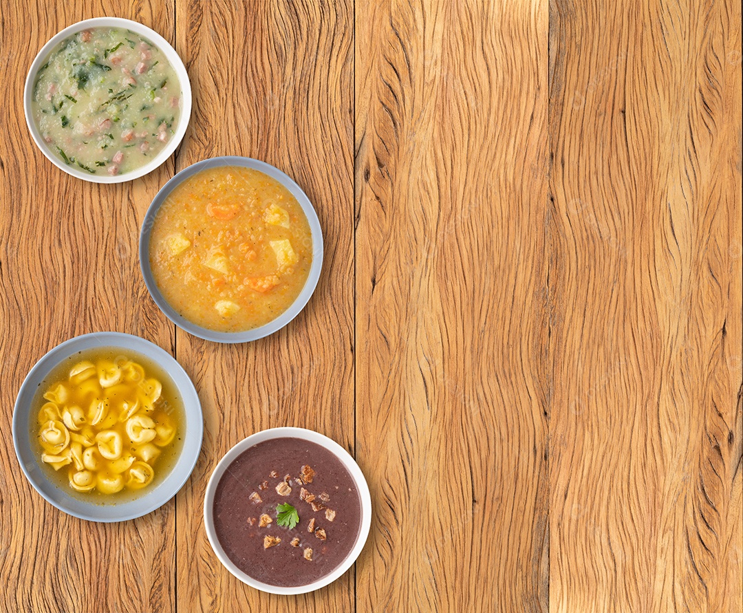Vários sabores de sopa em tigelas sobre a mesa de madeira.
