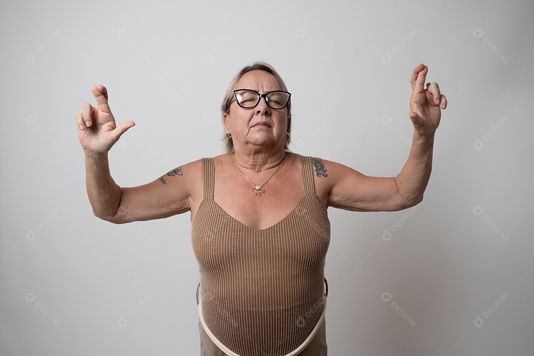 Adulto confiante com braços levantados, gesticulando, usando óculos, em fundo cinza.