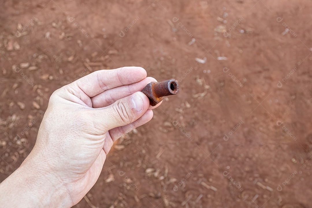 Mão branca segurando um pequeno pedaço de metal enferrujado