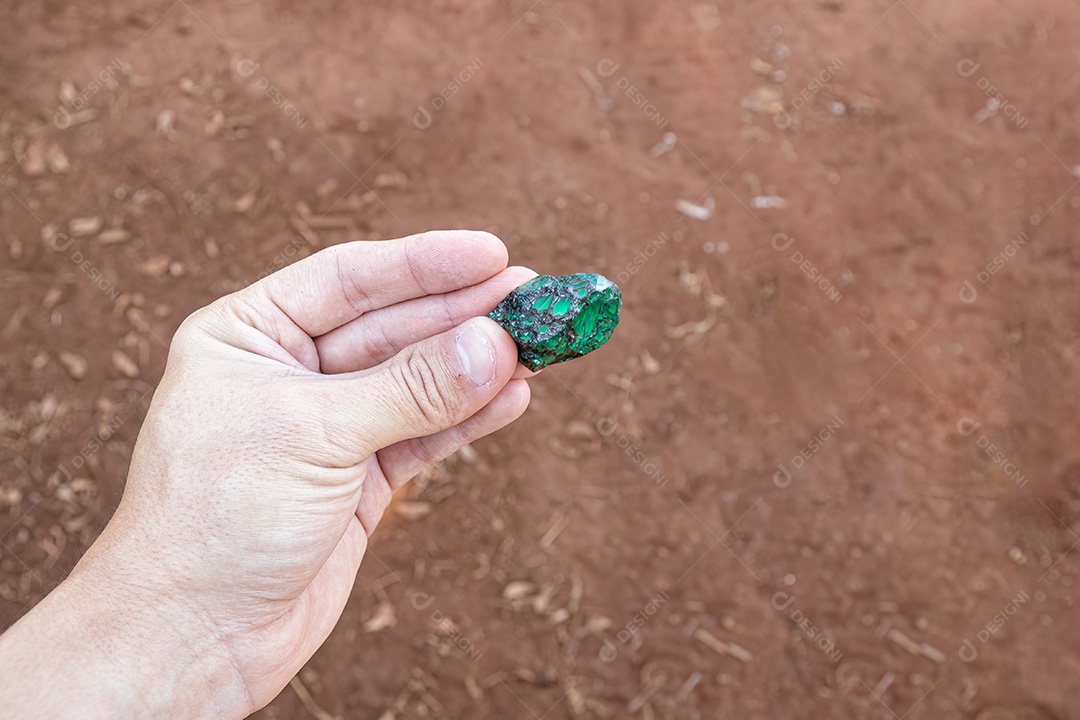Mão branca segurando um pequeno pedaço de esmeralda