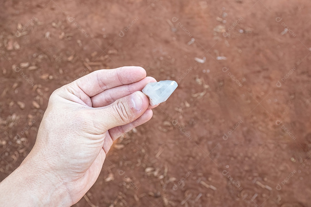 Mão branca segurando um pequeno pedaço de cristal de quartzo