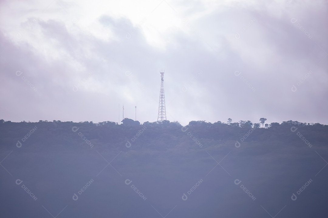 Torre telefônica em uma cordilheira com floresta no meio do nevoeiro