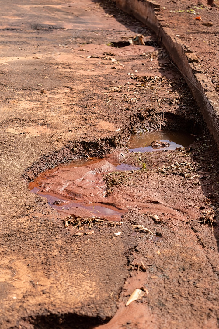 Buraco na rua de asfalto com poças de água