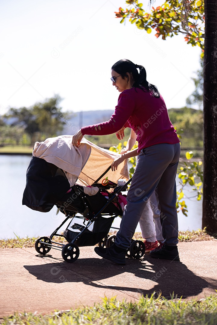 Carrinho de bebê com bebê recém-nascido sendo carregado pela mãe