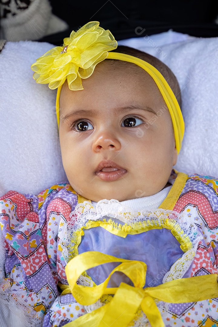 Menina recém-nascida no carrinho de bebê com roupas de festa e laço amarelo na cabeça