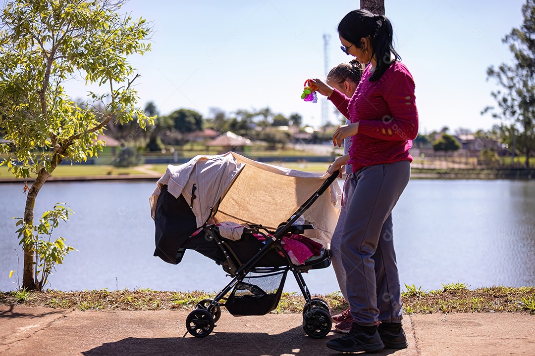 Carrinho de bebê com bebê recém-nascido sendo carregado pela mãe