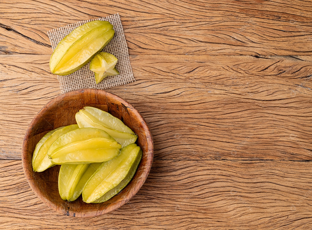 Um grupo de carambolas com fatias sobre a mesa de madeira com espaço de cópia.