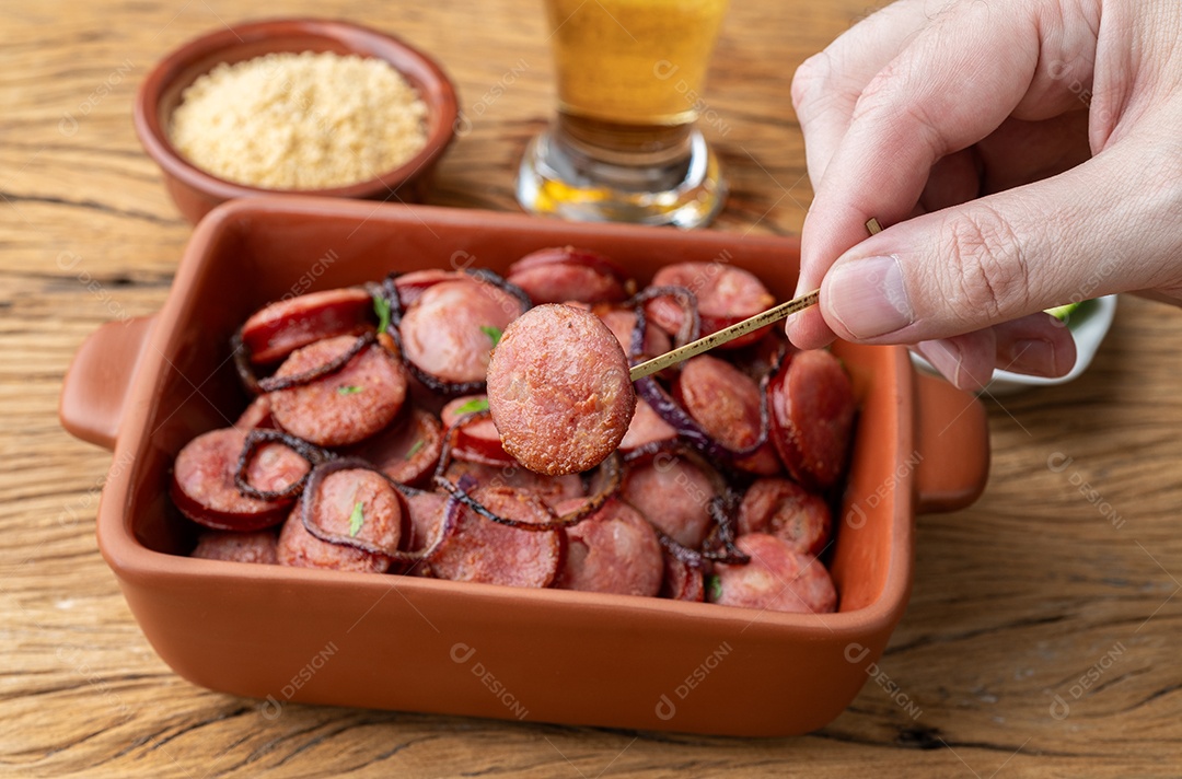 Escolhendo manualmente uma fatia de linguiça calabresa grelhada.