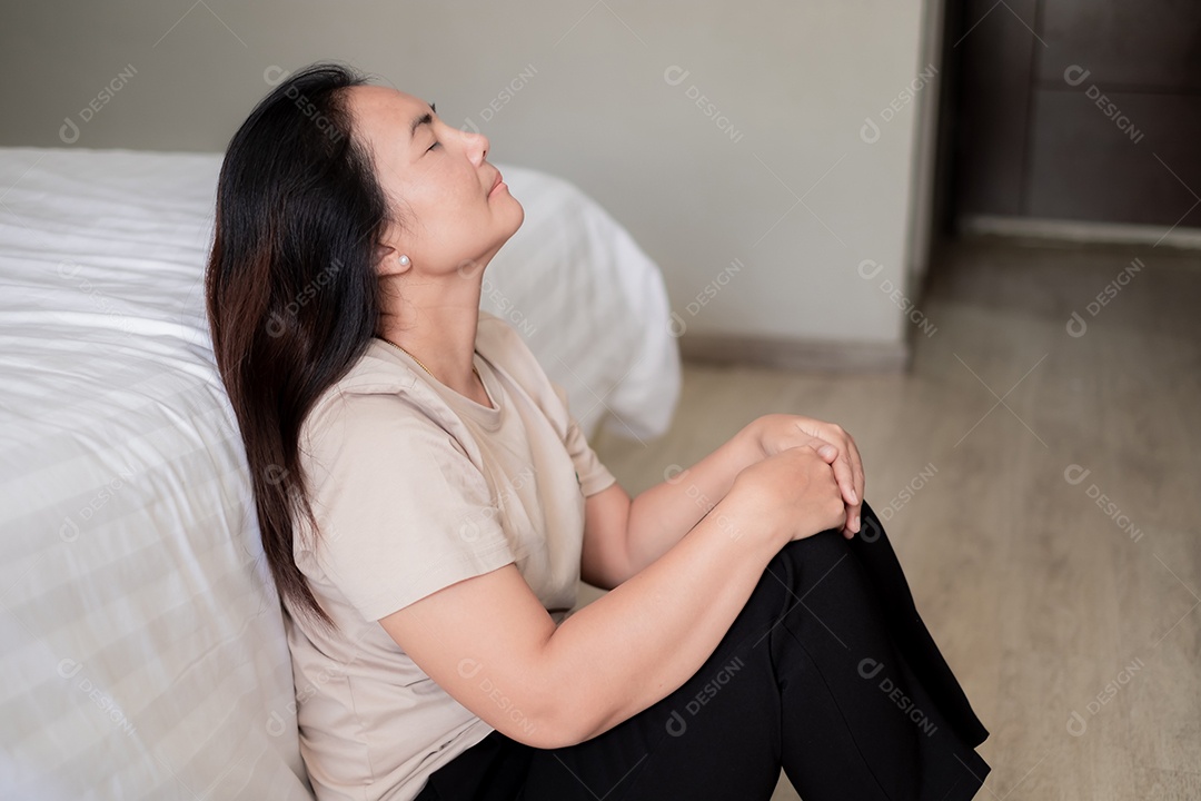 Triste mulher asiática deprimida sofrendo na cama branca, ela está sentada na cama e tocando a testa