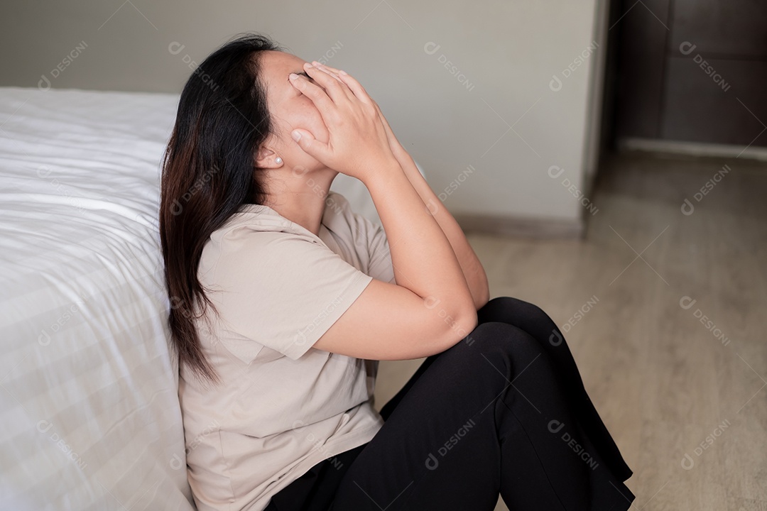 Triste mulher asiática deprimida sofrendo na cama branca, ela está sentada na cama e tocando a testa