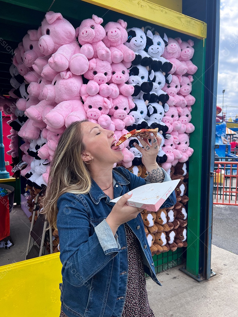 Uma linda menina comendo uma fatia deliciosa de pizza.