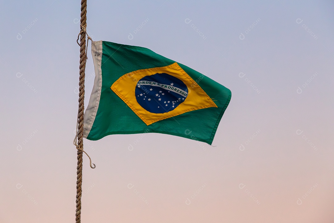 bandeira do brasil ao ar livre com um lindo céu colorido do pôr do sol no Rio de Janeiro.